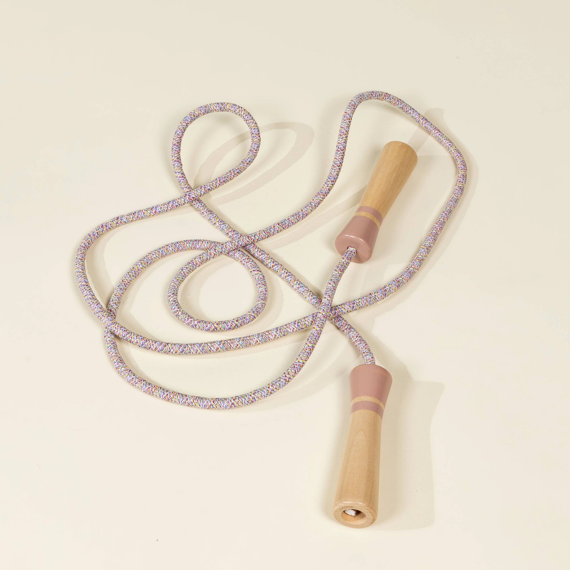 Purple jump rope with wooden handles on a beige background