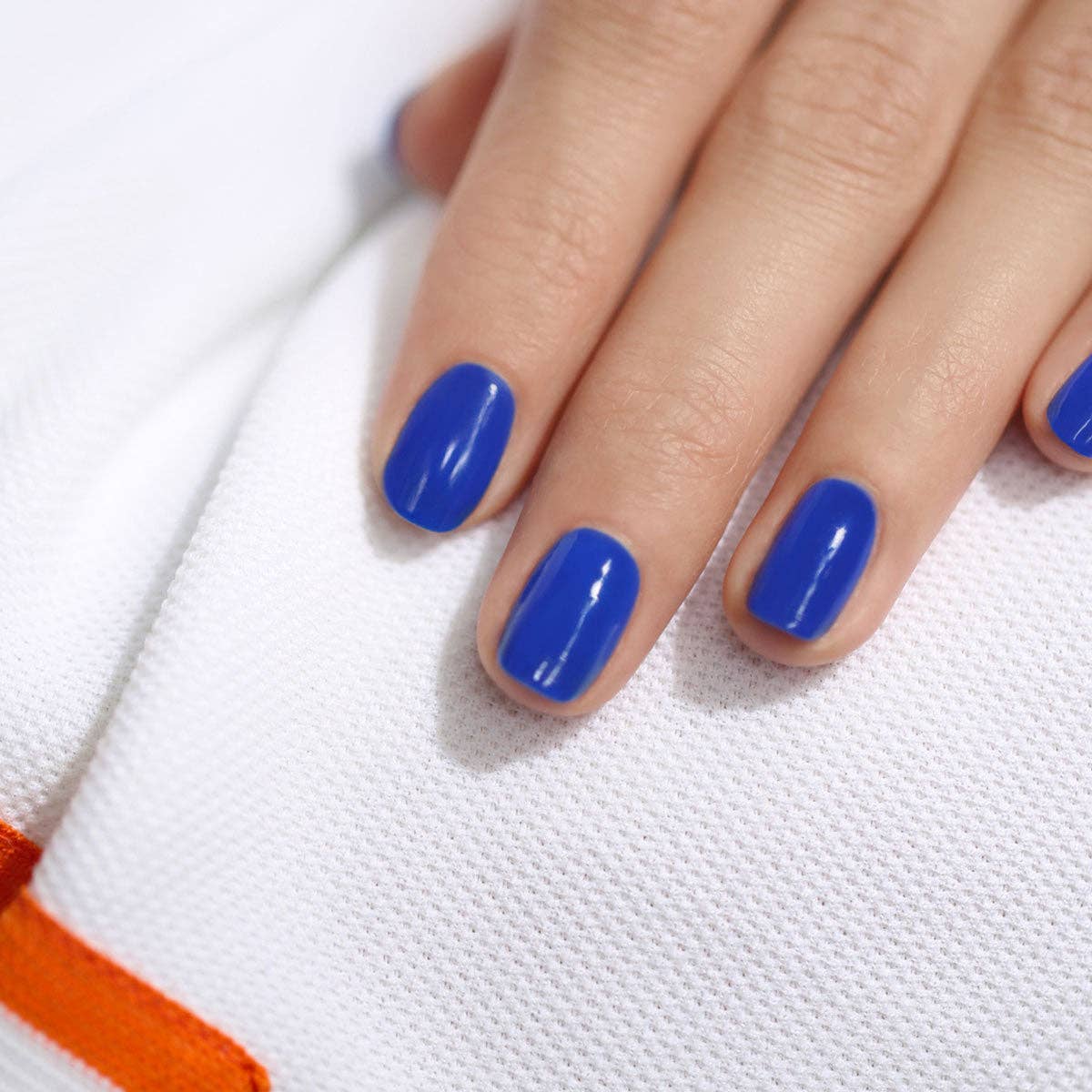 Hand with blue nail polish on a white background