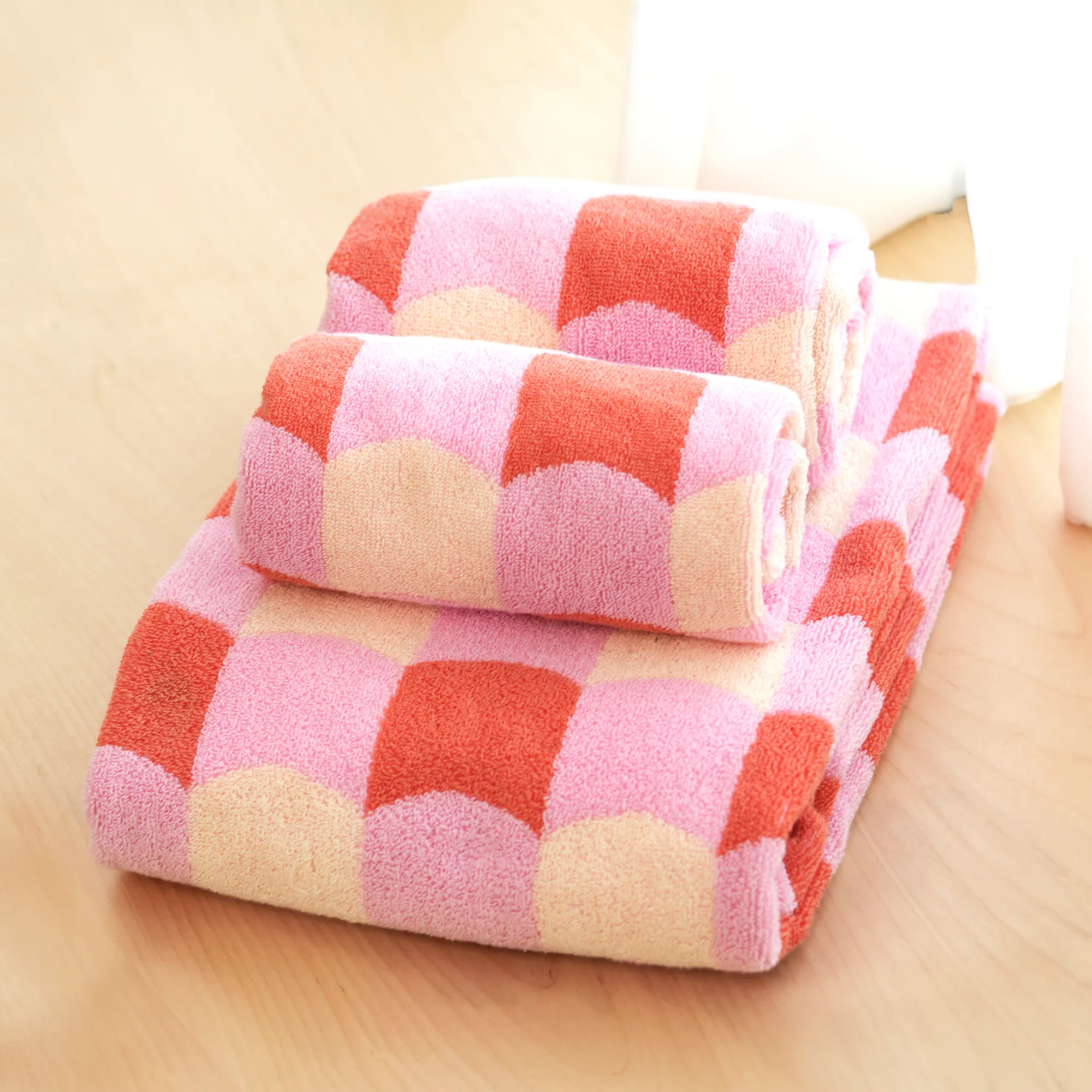 Stack of pink and red checkered towels on a beige surface