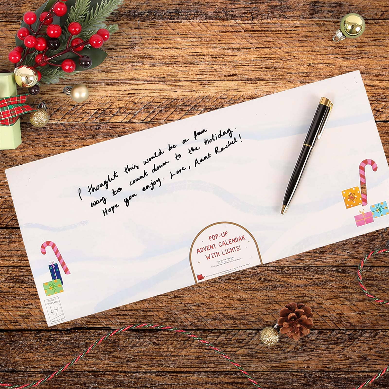 Letter with pen on a wooden surface with Christmas decorations
