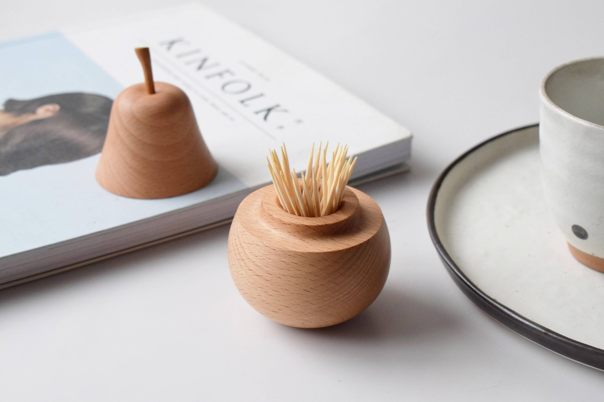 Wooden toothpick holder on a table with a magazine and plate in the background