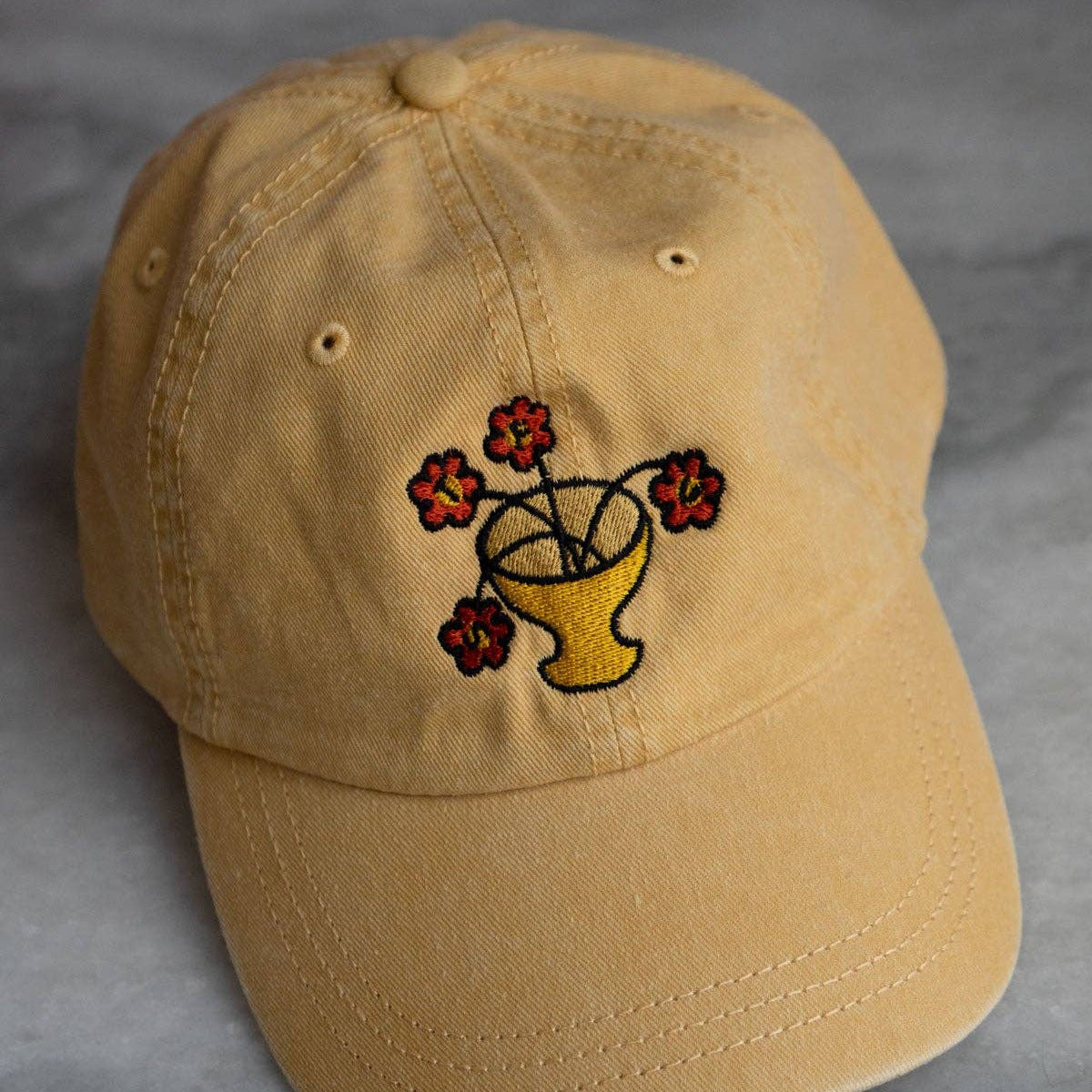 Beige cap with embroidered design on a gray background