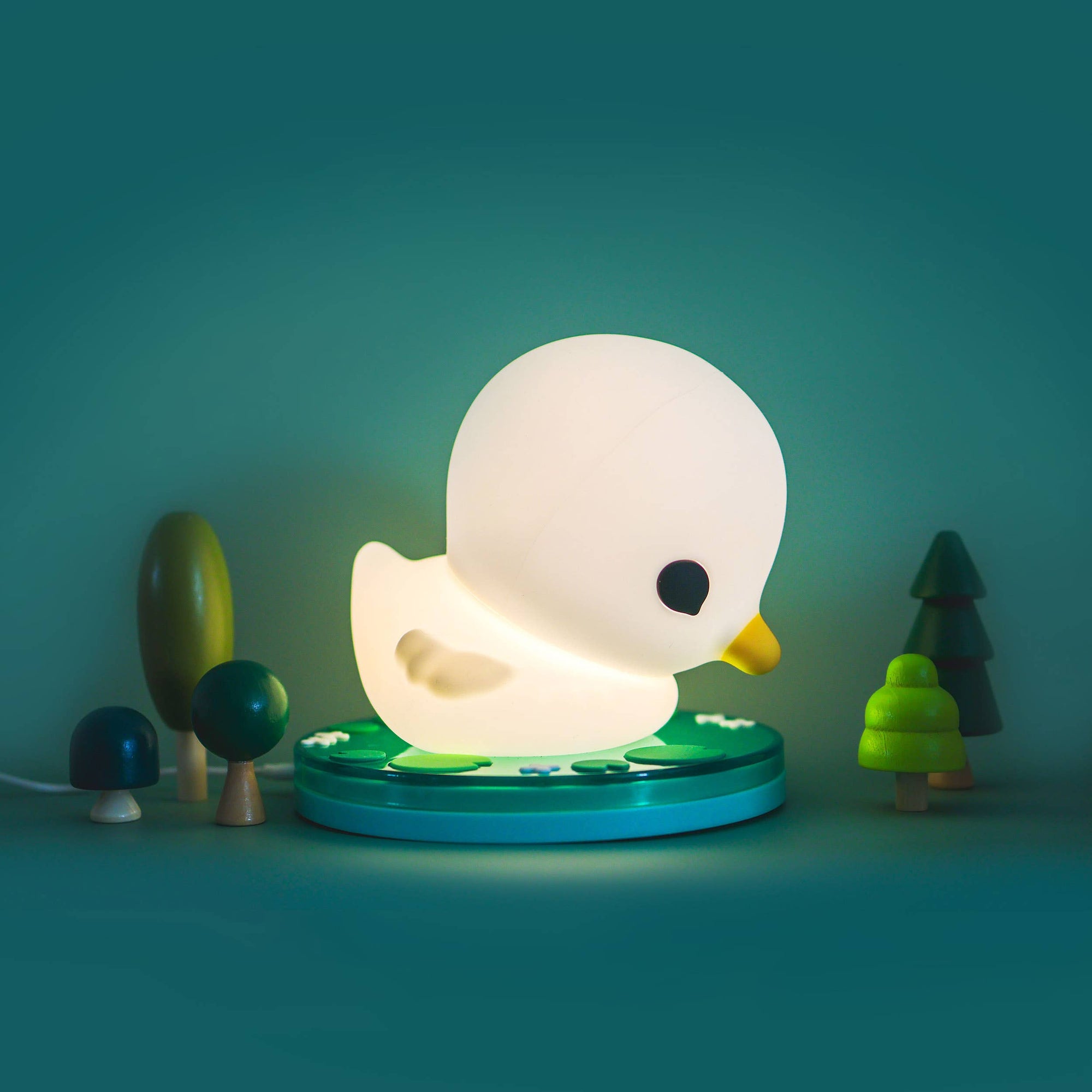 White duck-shaped night light on a green base with trees in the background