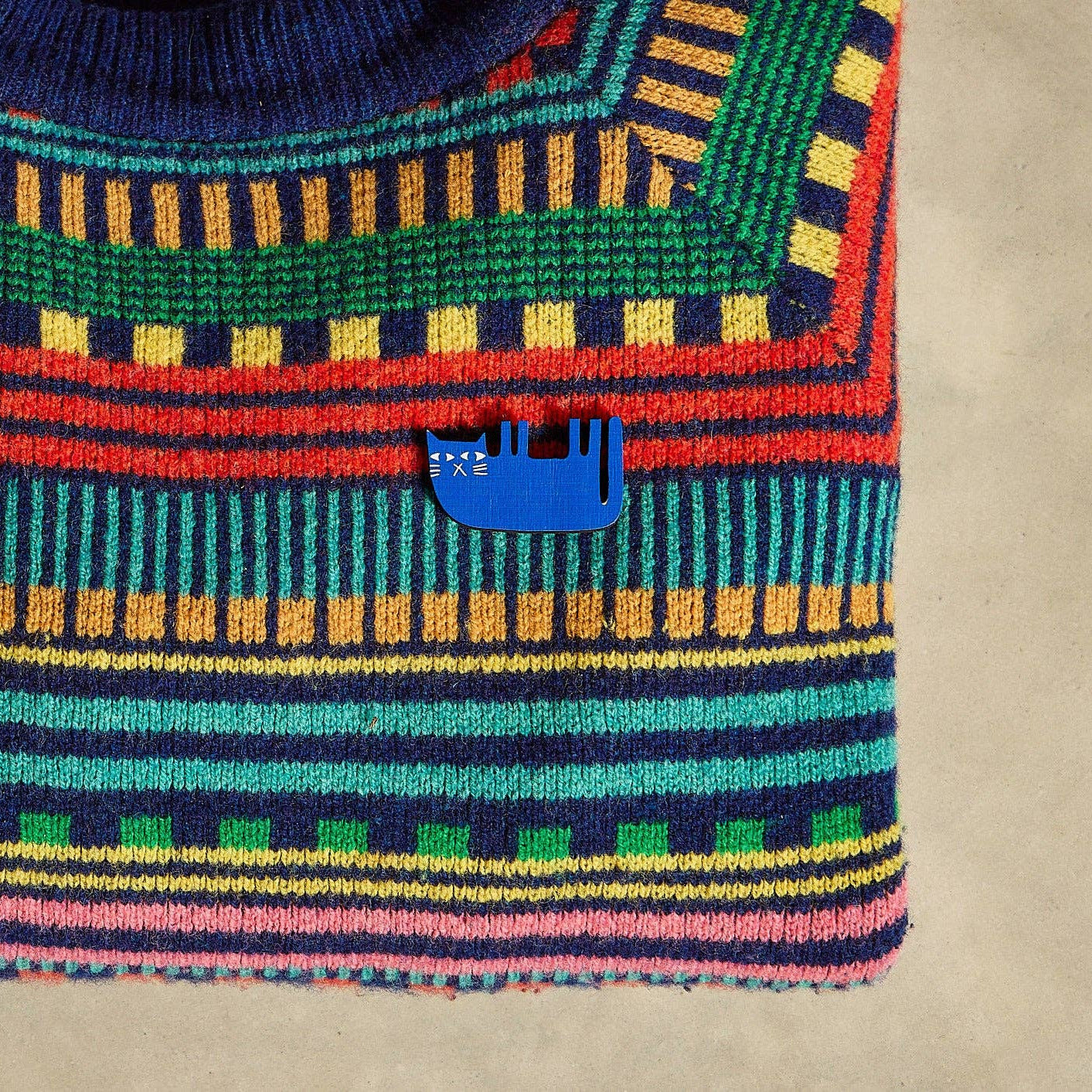 Colorful striped sweater with a blue logo on a beige background