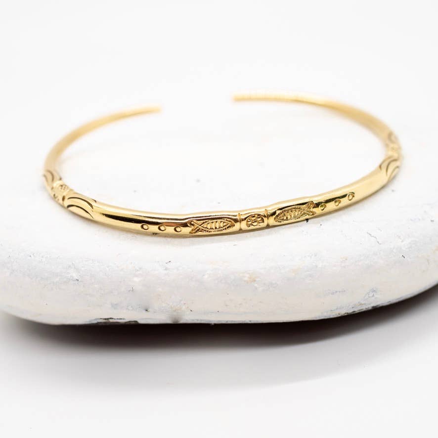 Gold bracelet with intricate design on a white stone surface