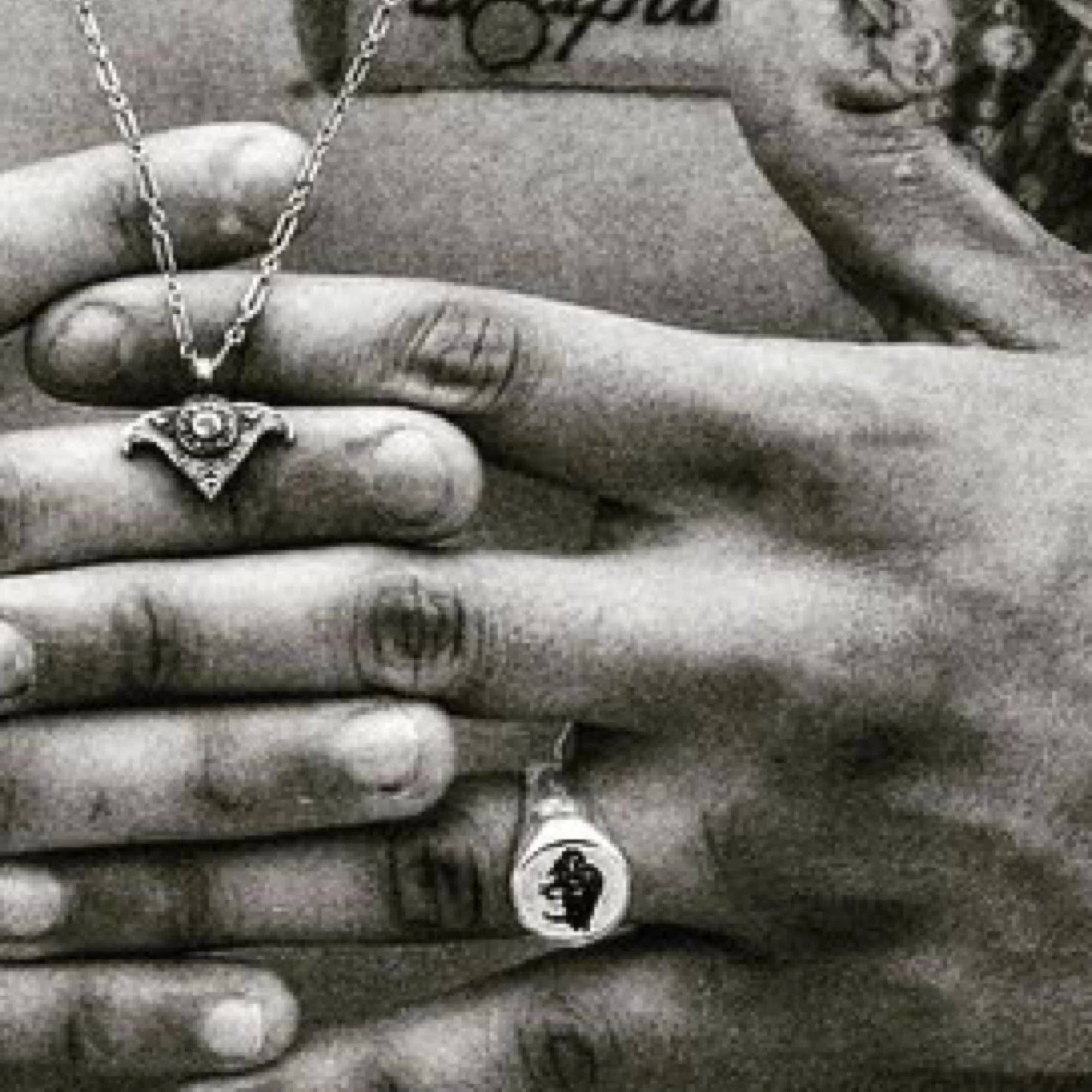 Close-up of hands wearing necklaces and rings with a blurred background