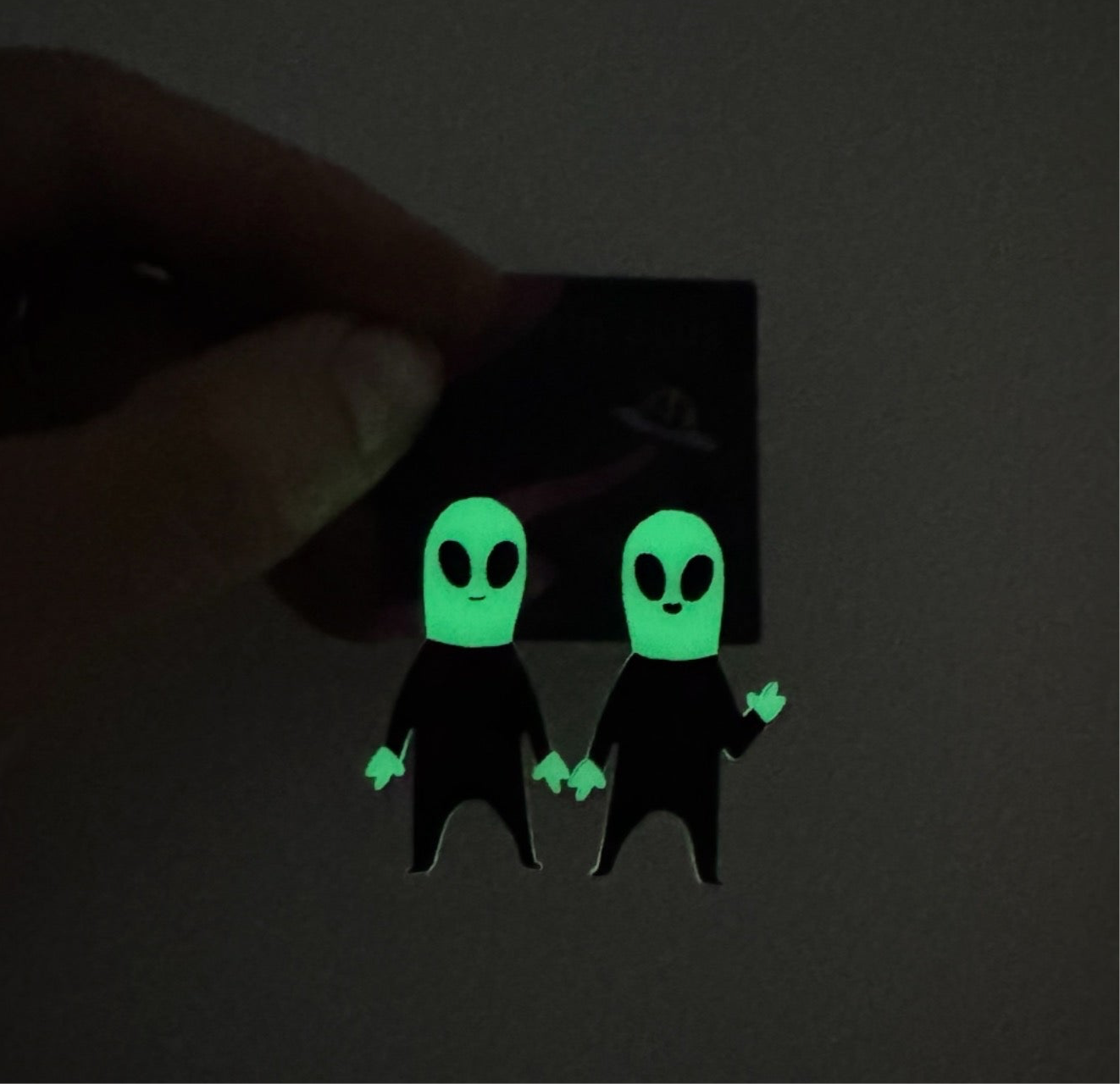 Glowing green alien figures on a dark background