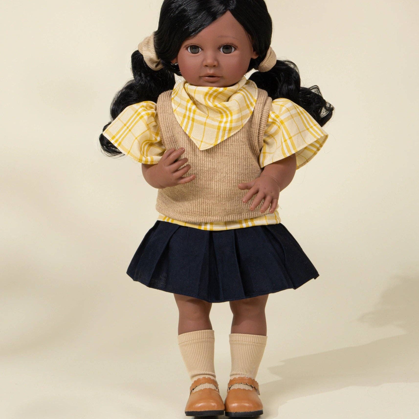 Doll wearing a yellow blouse, beige vest, and navy skirt on a plain background