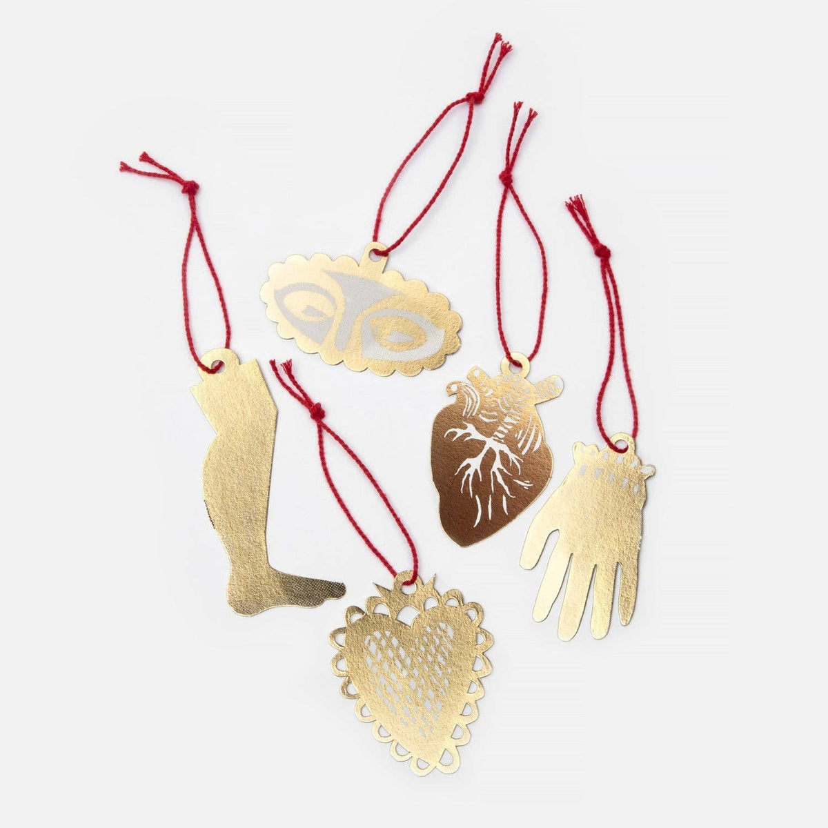Gold decorative ornaments with intricate designs on red strings against a white background