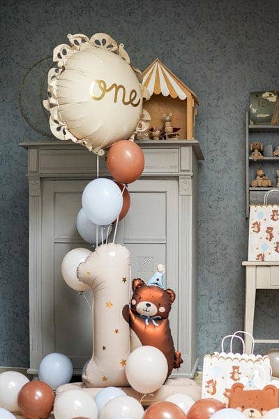 Decorative balloons with a teddy bear and 'one' balloon in a room setting.