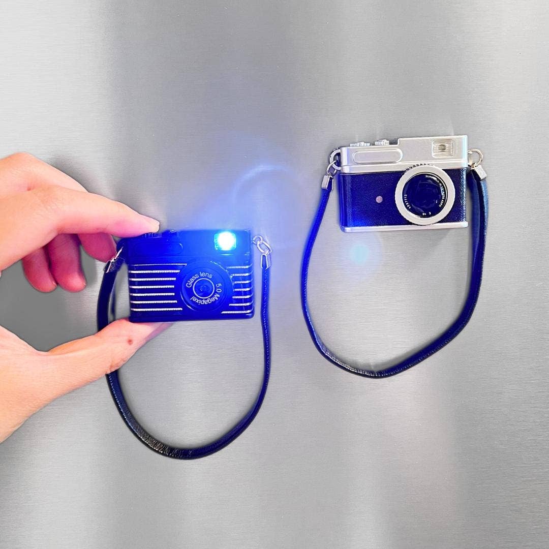 Small blue camera with a strap, held by a hand on a gray background