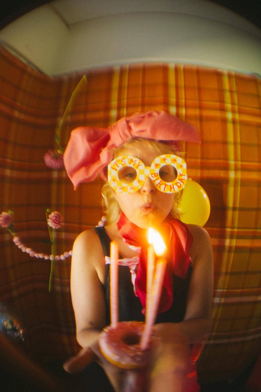 Person blowing out candles on a birthday cake with a plaid background