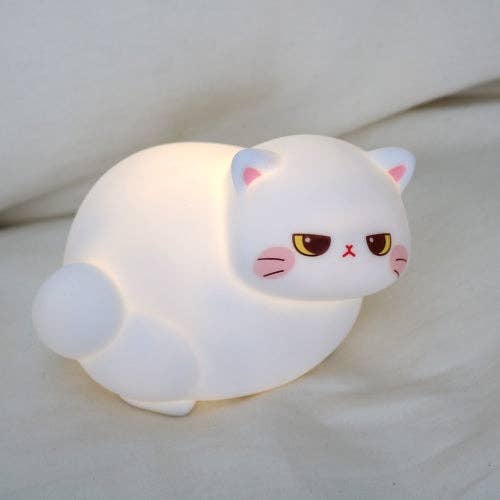 Cute white cat-shaped night light on a soft surface