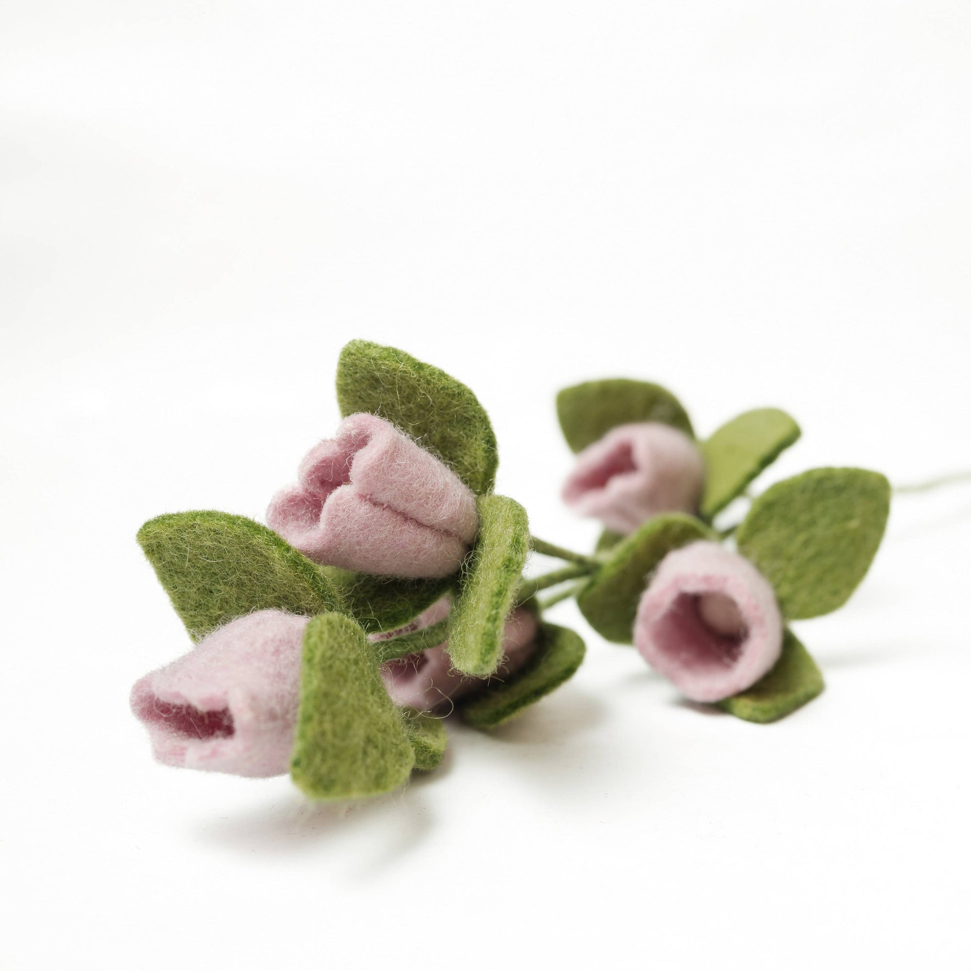 Felted flower bouquet with pink flowers and green leaves on a white background
