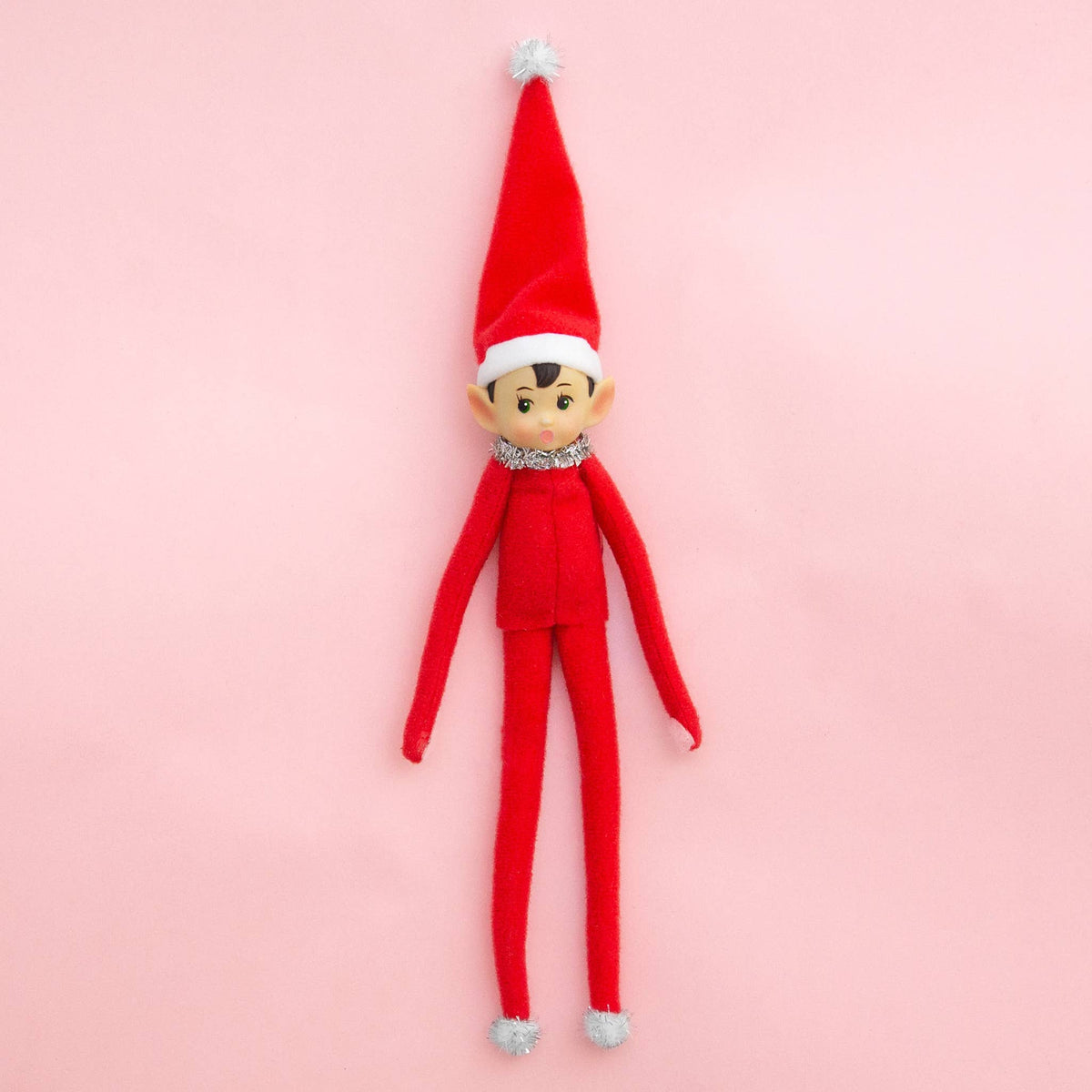 Red elf doll with a red hat on a pink background