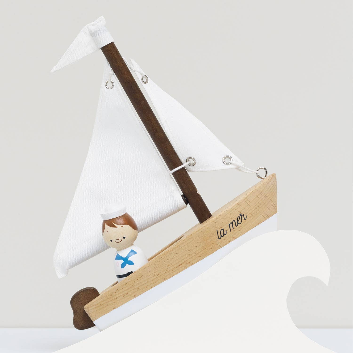Decorative sailboat with a figure of a boy and 'la mer' on a white background