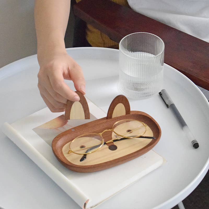 Wooden eyeglass case shaped like a fox with glasses inside, on a white surface.