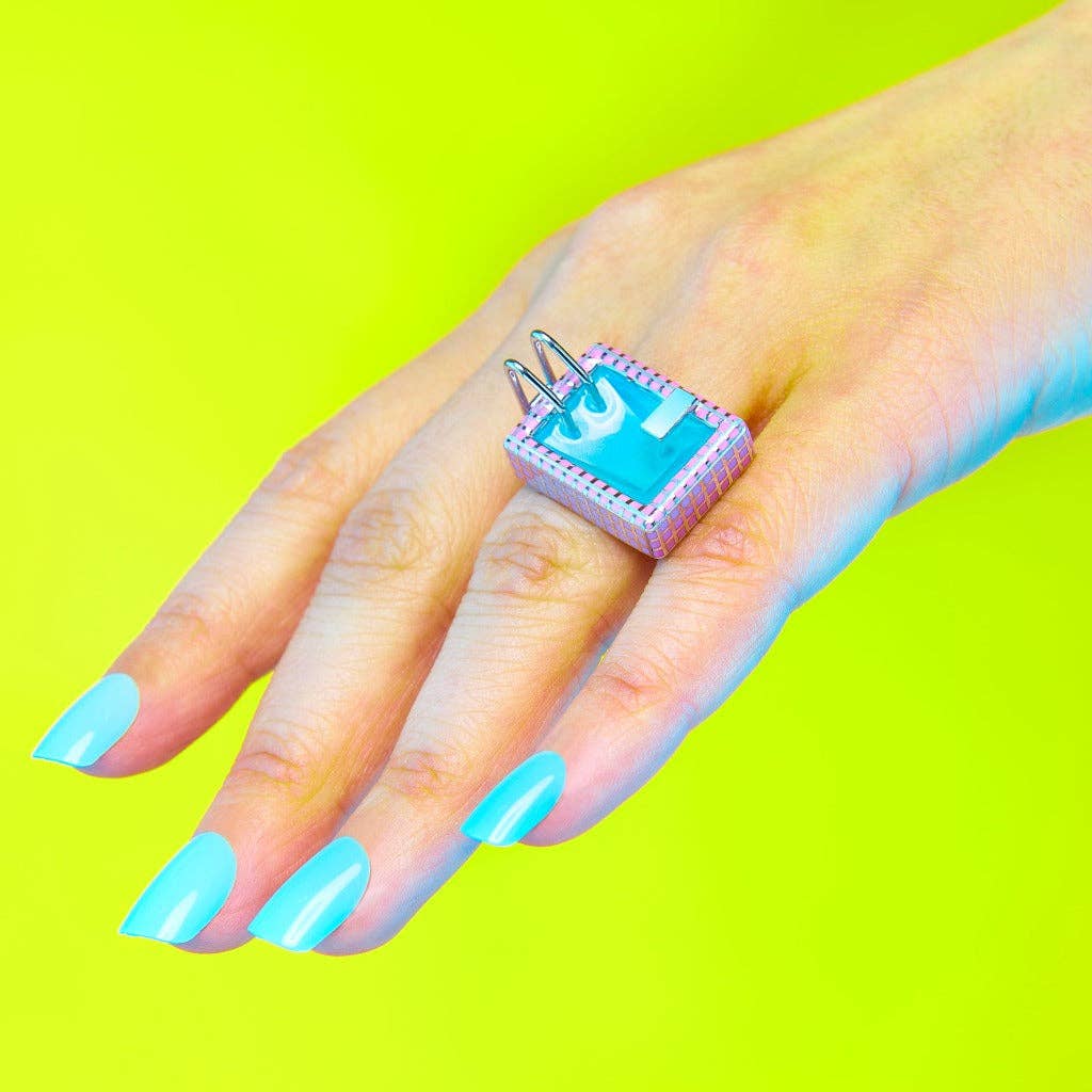 Hand wearing a futuristic ring with a turquoise gem against a bright green background