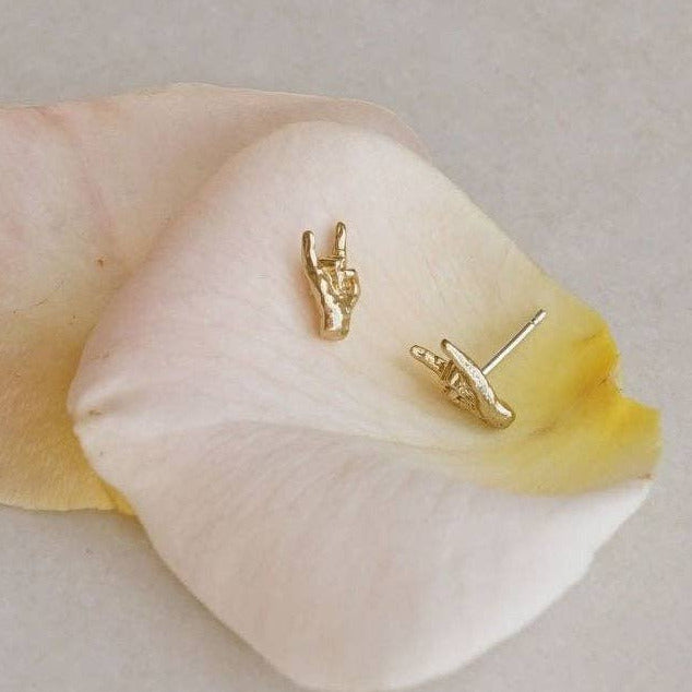 Gold earrings on a white petal with a light gray background