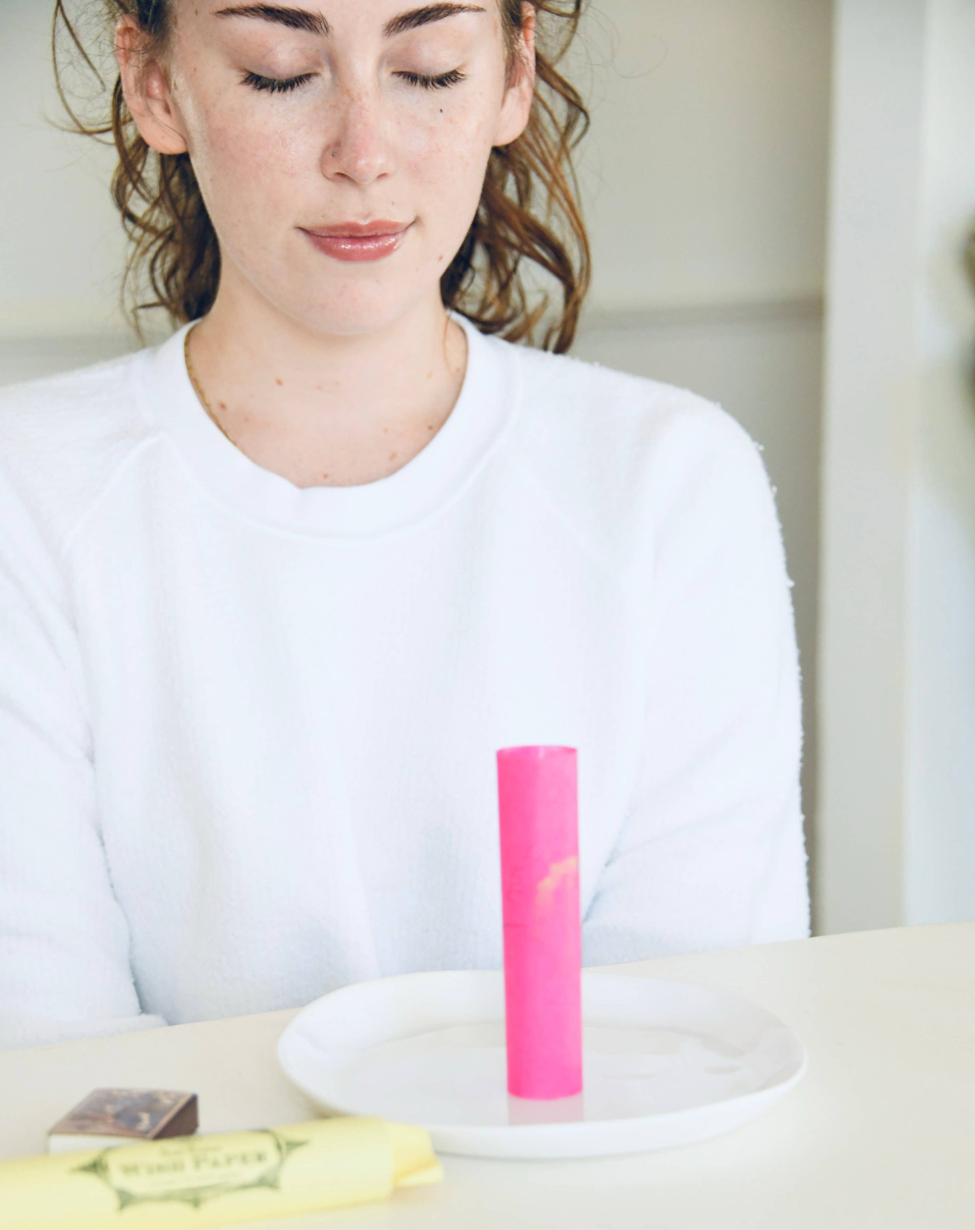 Woman sitting at a table with a pink piece of paper in front of her
