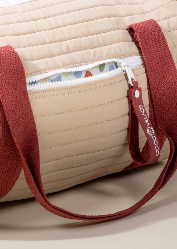 Beige quilted bag with red strap and visible brand logo on a neutral background