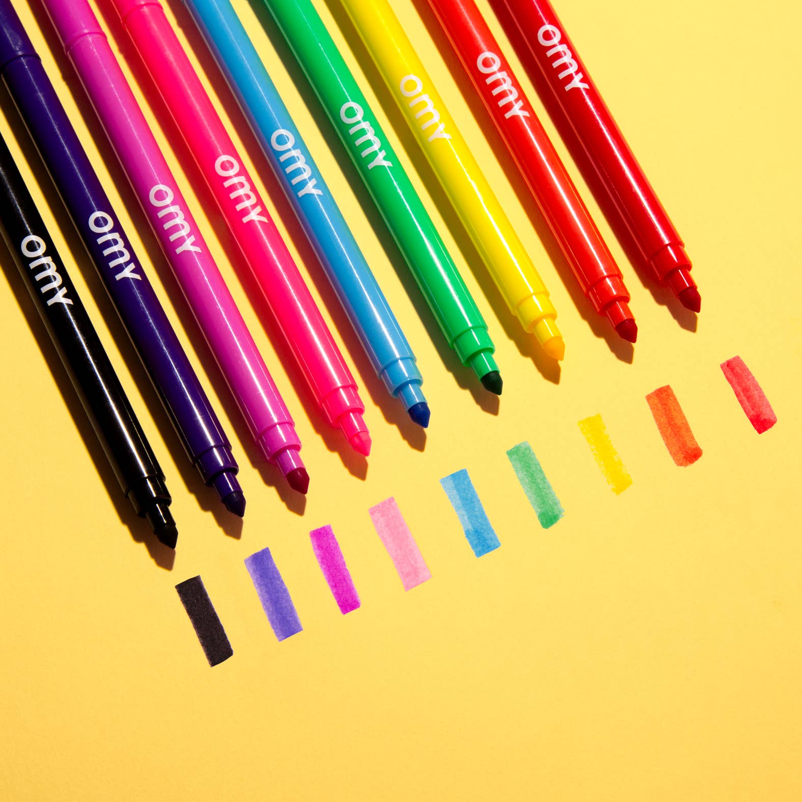 Colorful markers with visible brand name on a yellow background