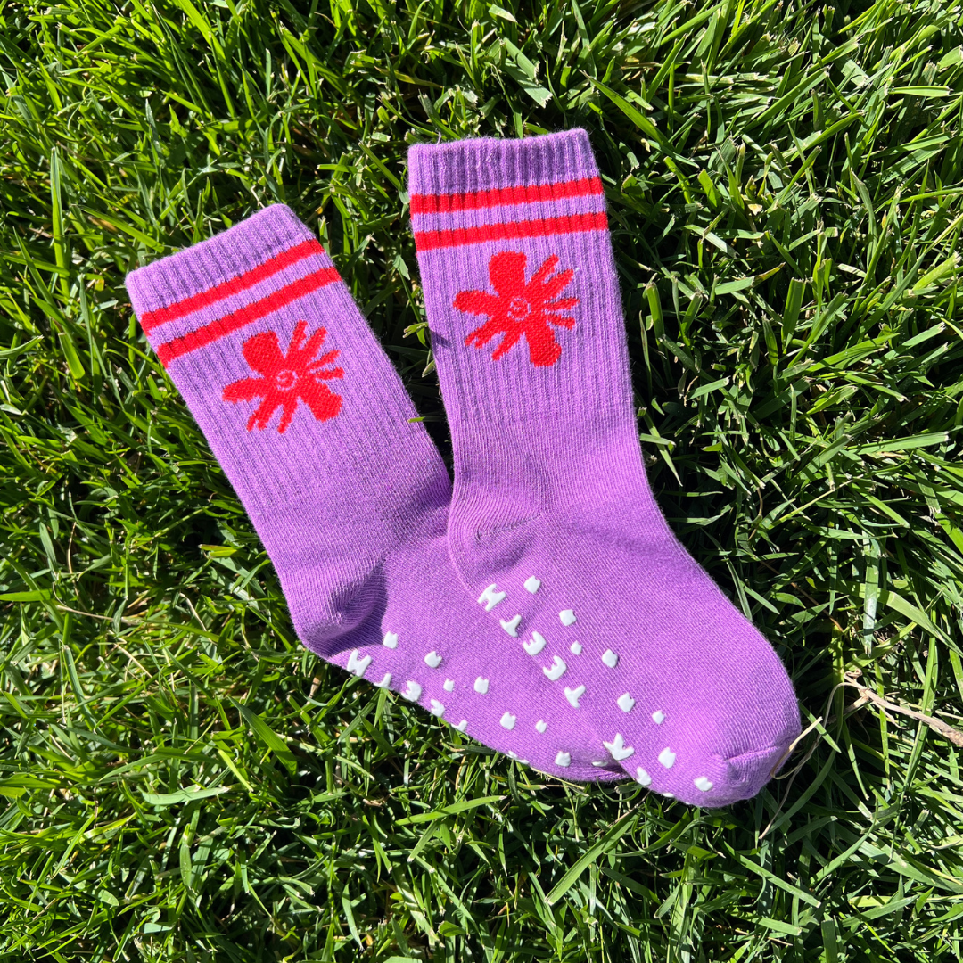 Purple socks with red star designs on grass