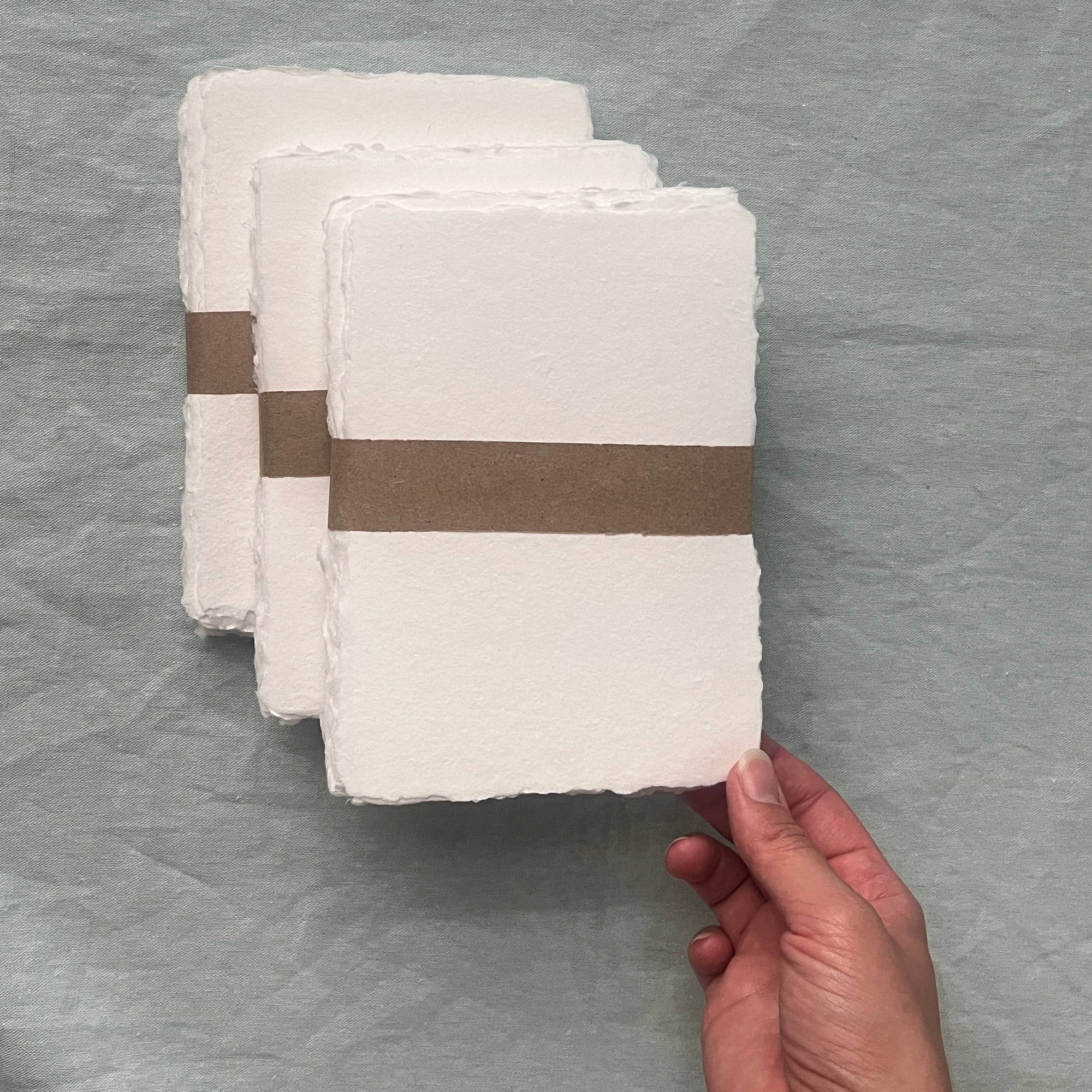 Stack of white sheets with a brown band held by a hand on a gray background