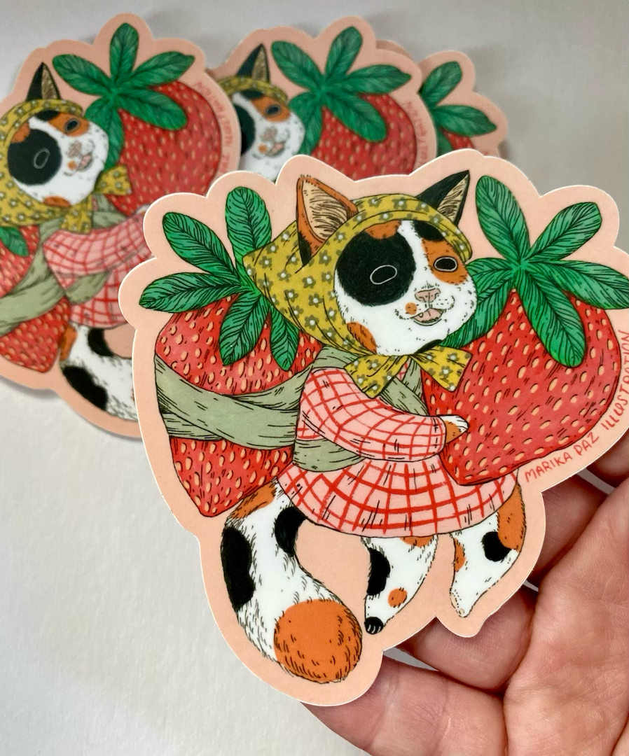Sticker of a cat in a strawberry costume held by a hand