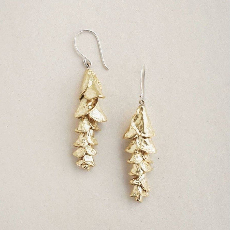 Gold leaf-shaped earrings on a light gray background