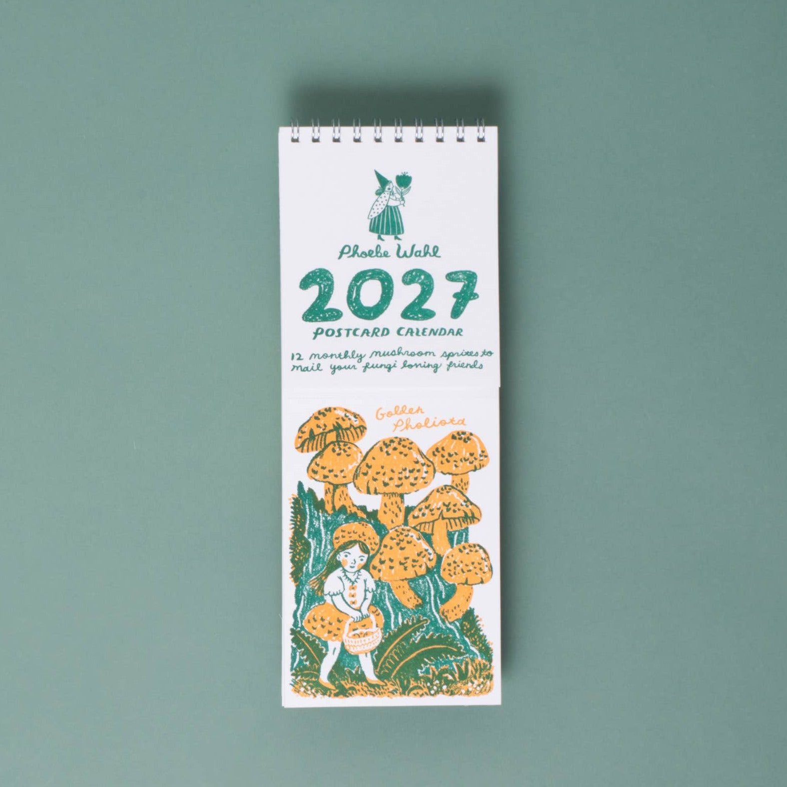 A vertical desk calendar 2027 featuring a white cover with green text and an illustration of a child among orange and yellow mushrooms, set against a solid sage green background.