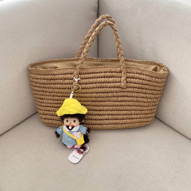 Woven bag with a plush toy keychain on a beige couch