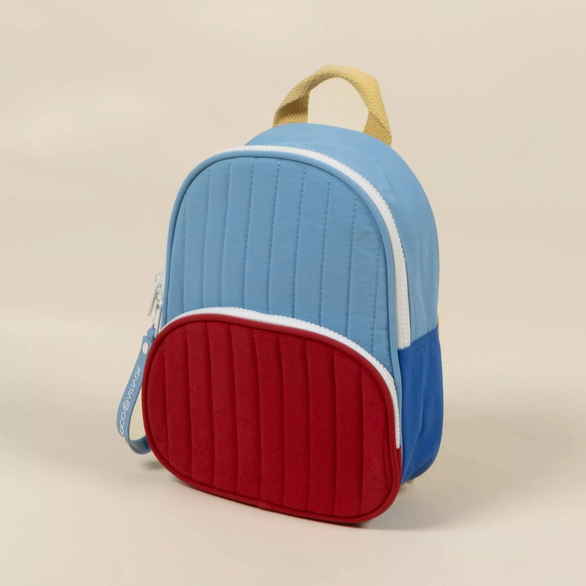 Children's backpack with blue top and red bottom on a beige background