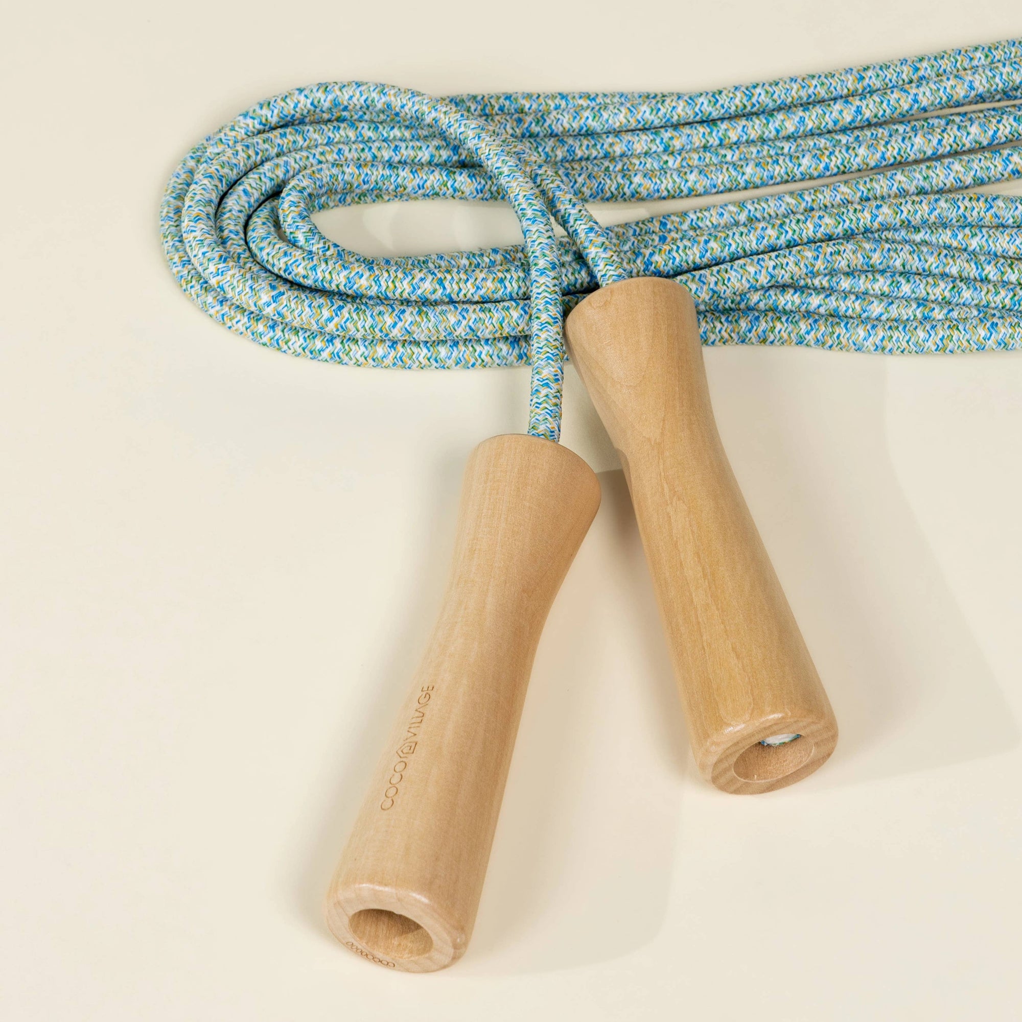 Blue and white rope skipping jump rope with wooden handles on a beige background