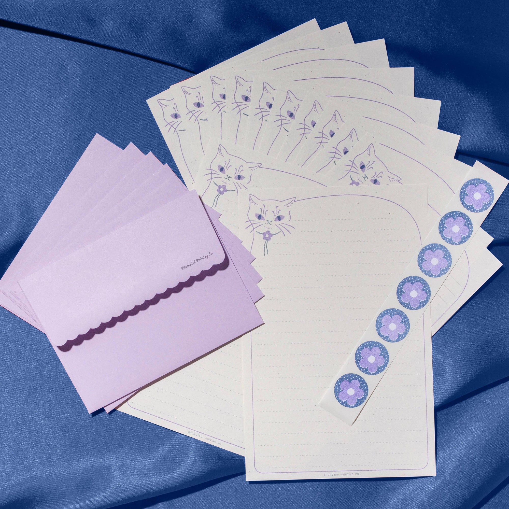 Set of stationery items including cards and envelopes with cat illustrations on a blue background