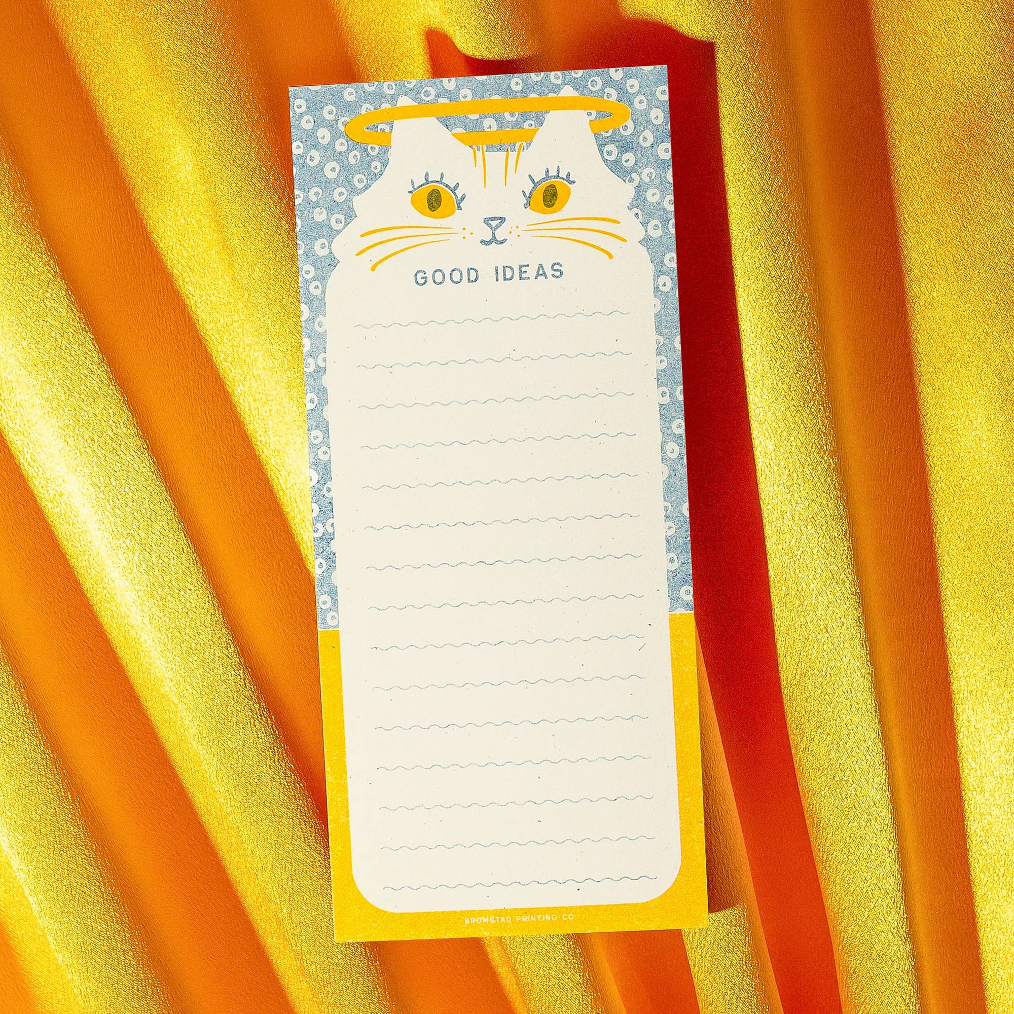 Notepad with a cat illustration and 'Good Ideas' text on a yellow and orange striped background