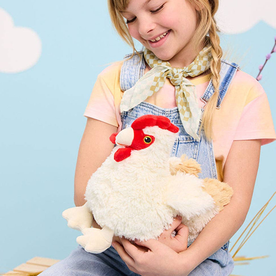 Young girl holding a plush rooster toy against a light blue background