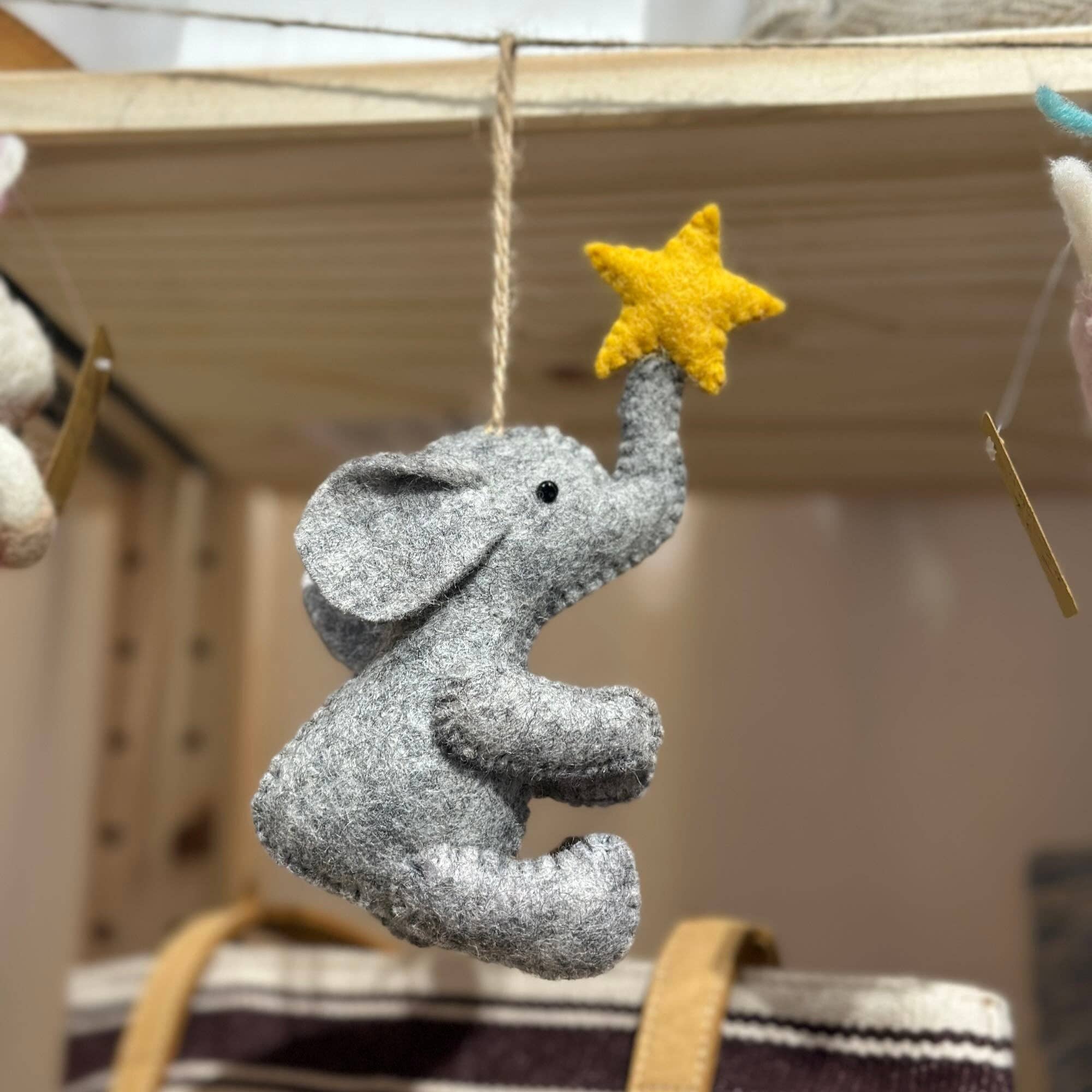 Gray elephant toy with a yellow star on a wooden shelf