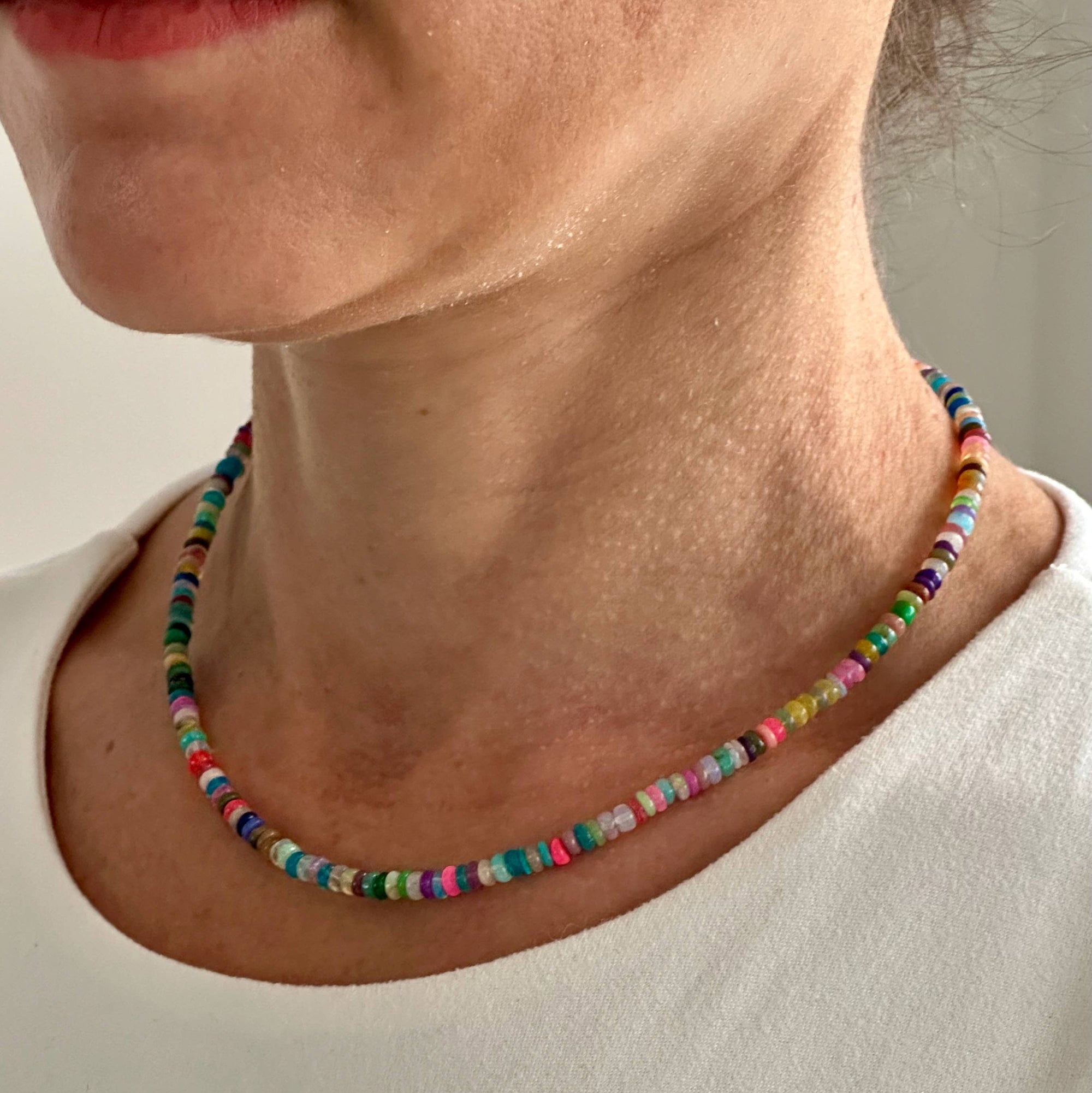 Multicolored beaded necklace worn by a person against a neutral background