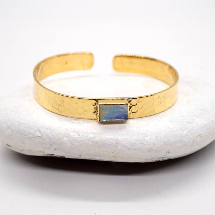 Gold bracelet with a gemstone on a white stone surface