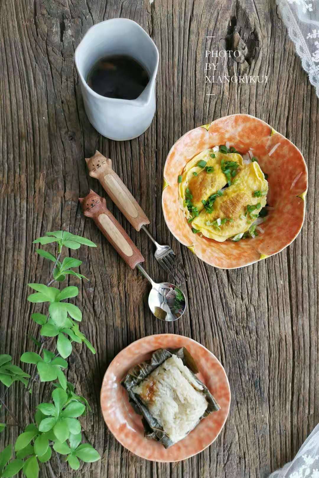 Two small plates with food on a wooden surface, accompanied by a cup and utensils.