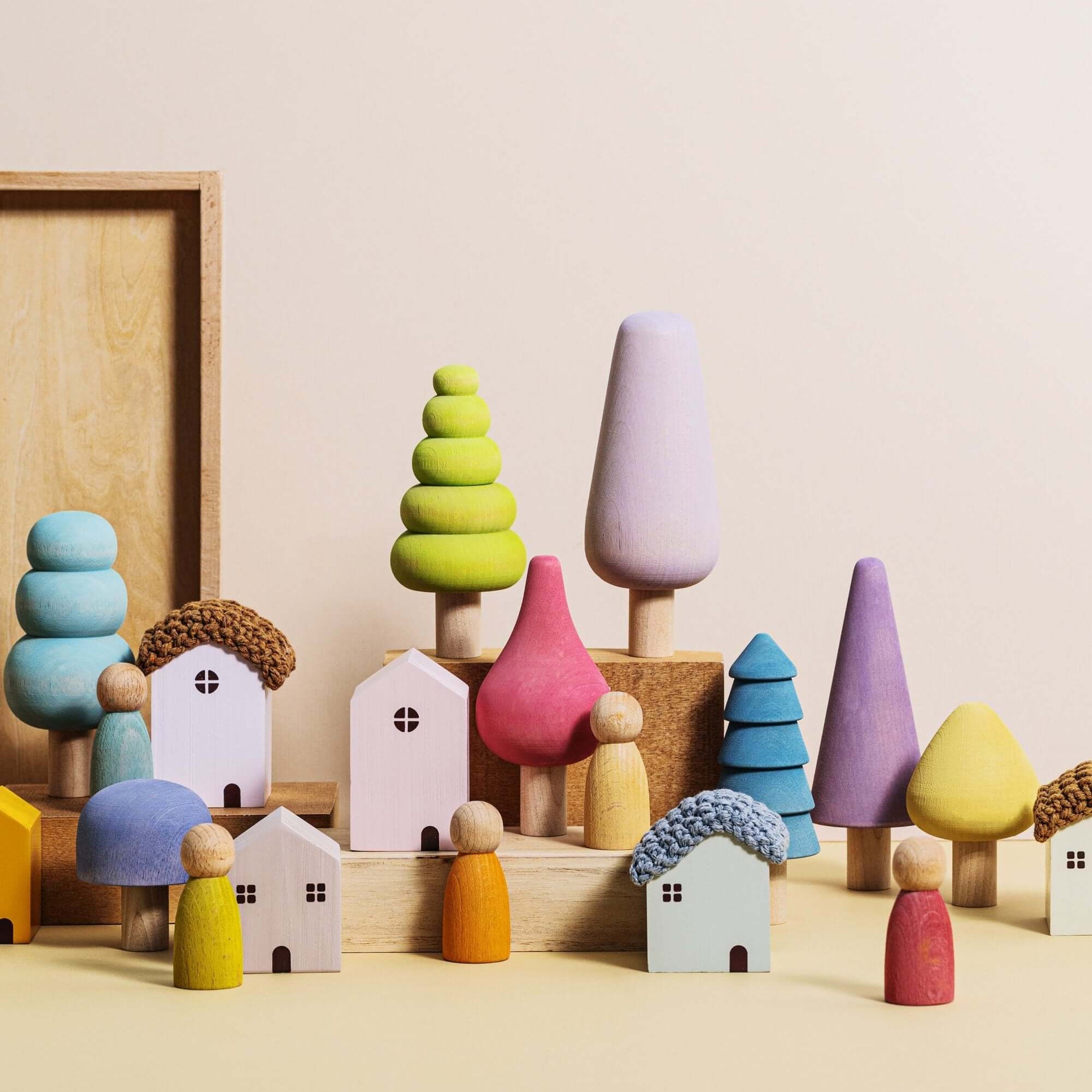 Colorful wooden toy houses and trees on a beige surface with a neutral background