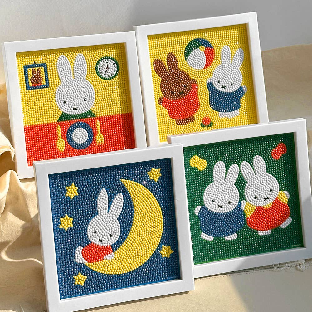 Four framed needlepoint pictures of cartoon bunnies on a light beige background