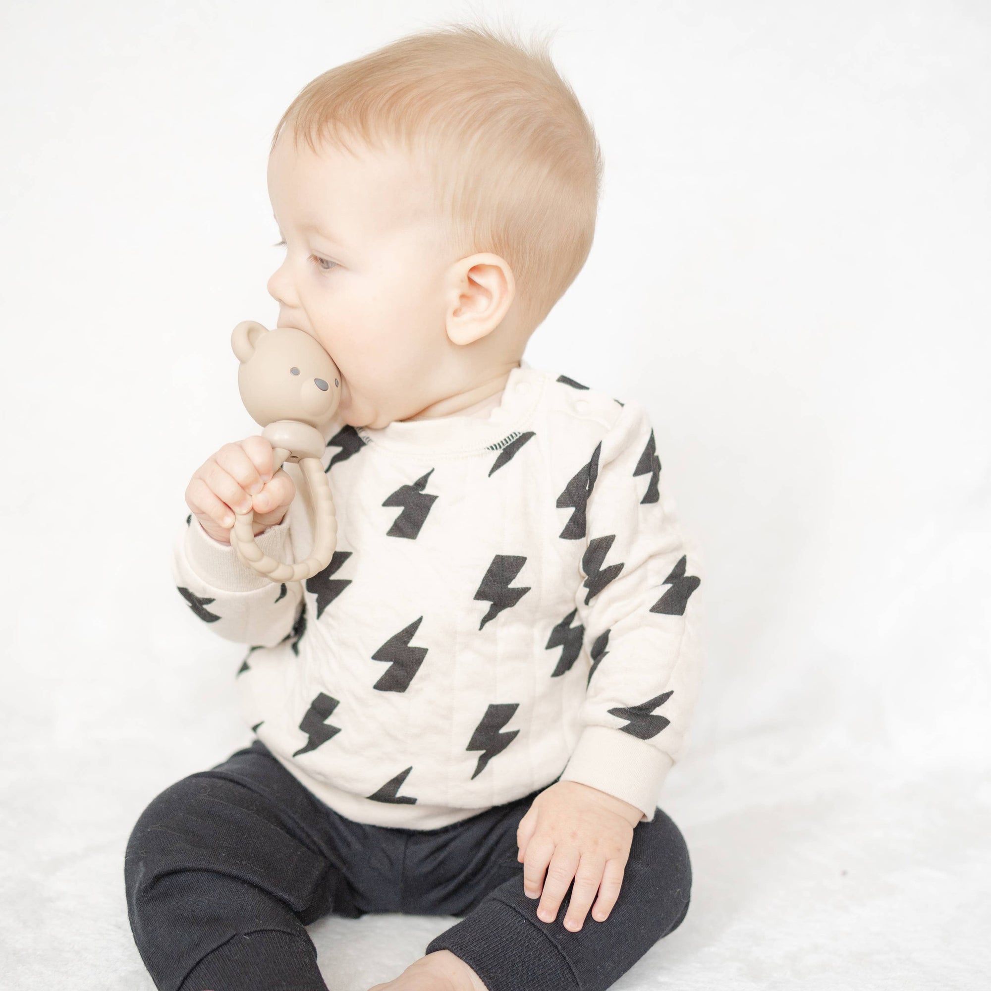 Baby wearing a white sweater with black patterns and dark pants on a white background