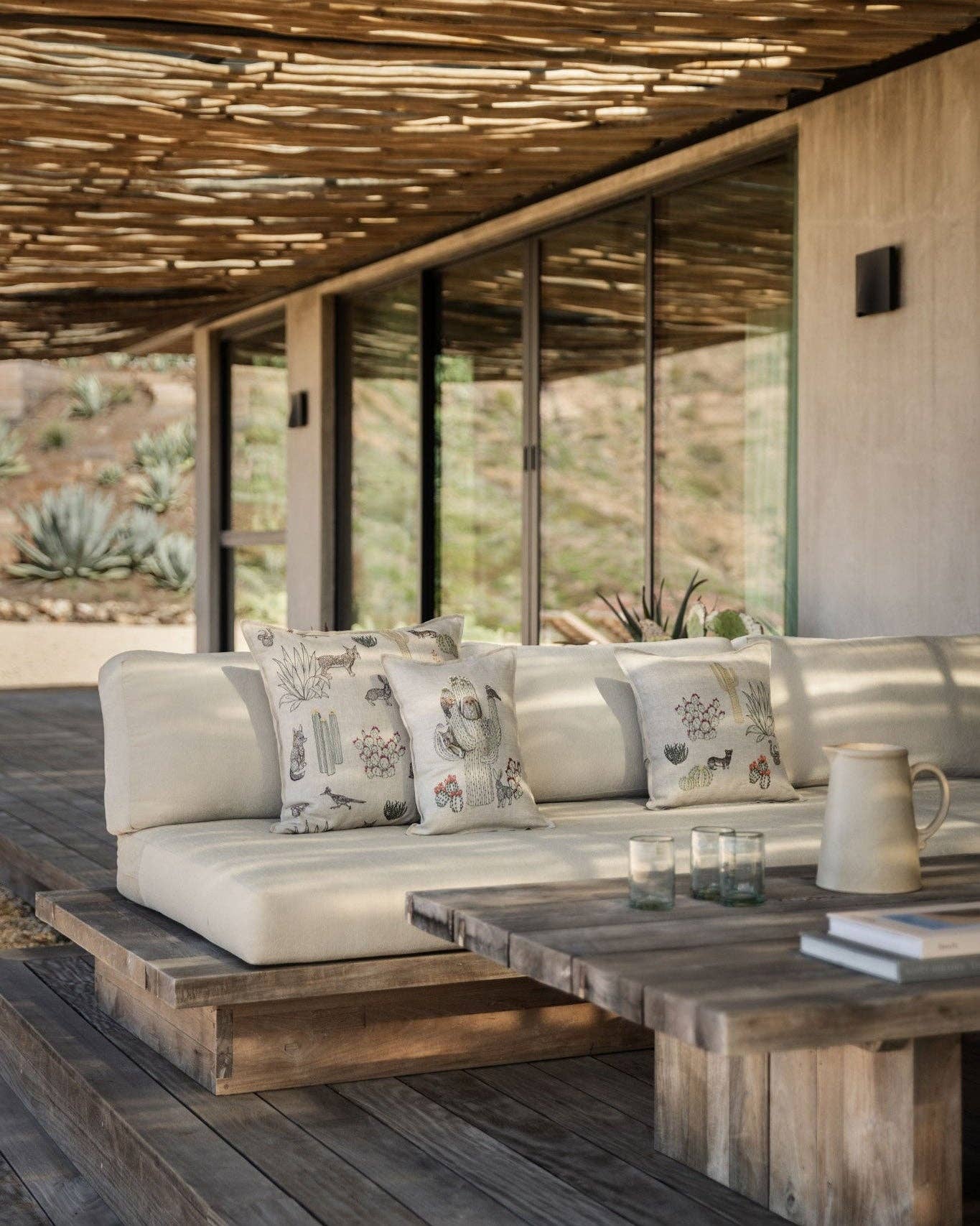 Outdoor living space with a white sofa, patterned cushions, and a wooden table.