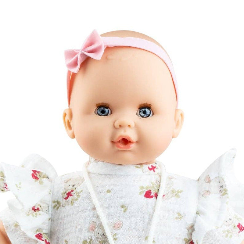 Baby doll wearing a white floral outfit with a pink headband on a white background