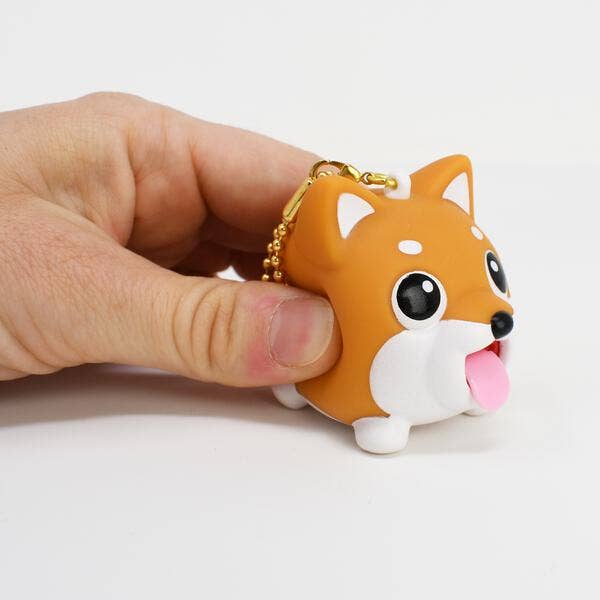 Hand holding a small dog-shaped keychain with a plain background