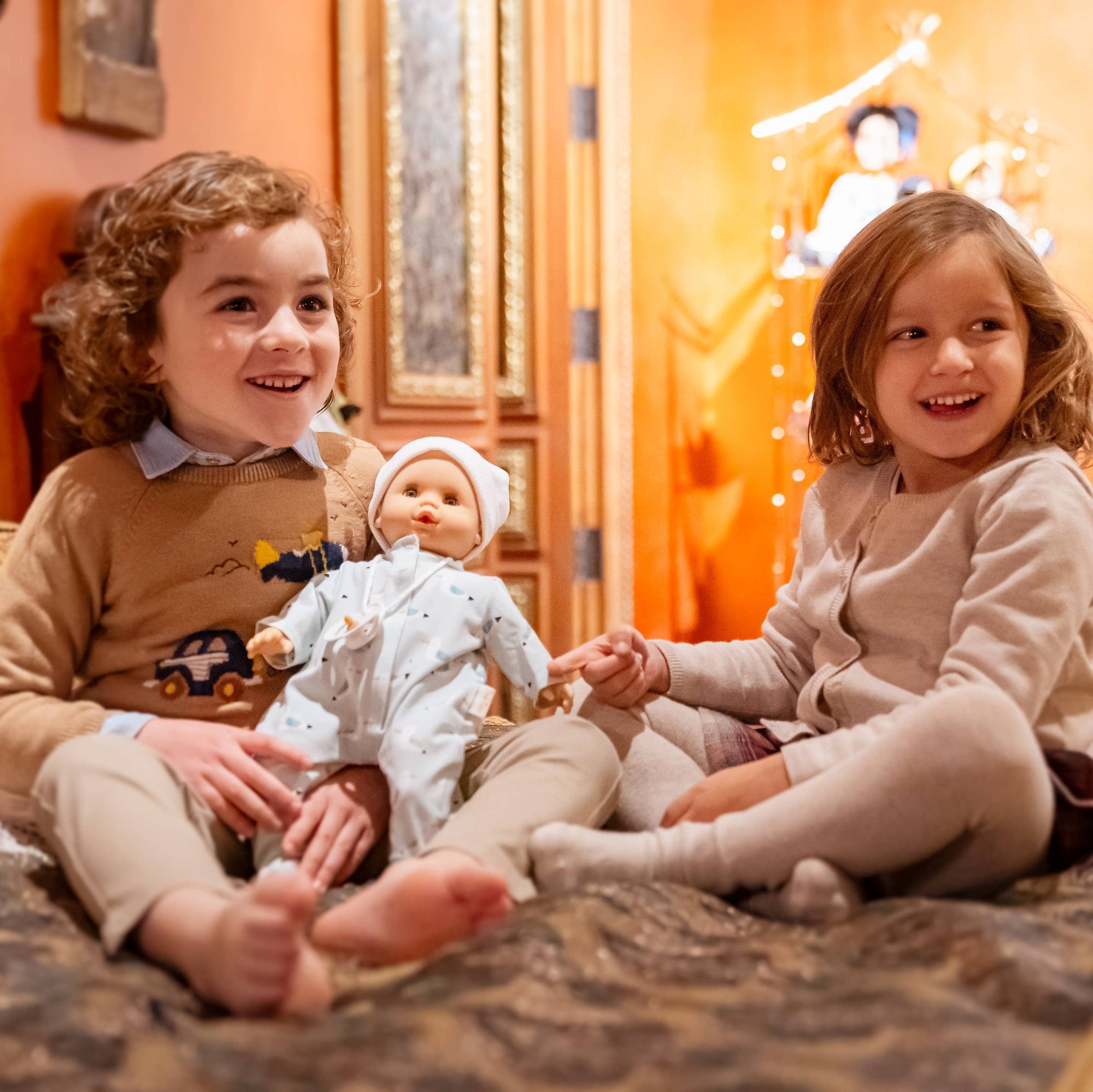 Two children playing with dolls in a cozy room.