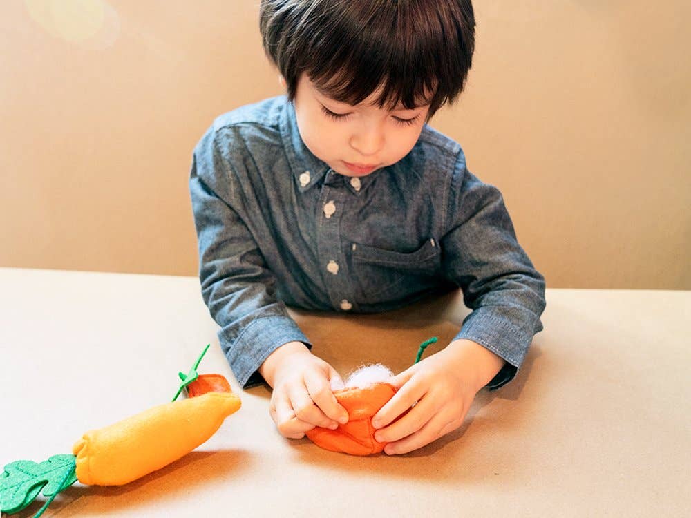 Child playing with toy vegetables on a table