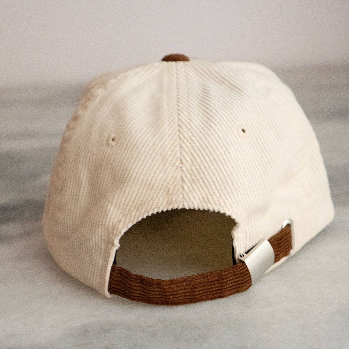 Beige cap with brown brim on a light gray background